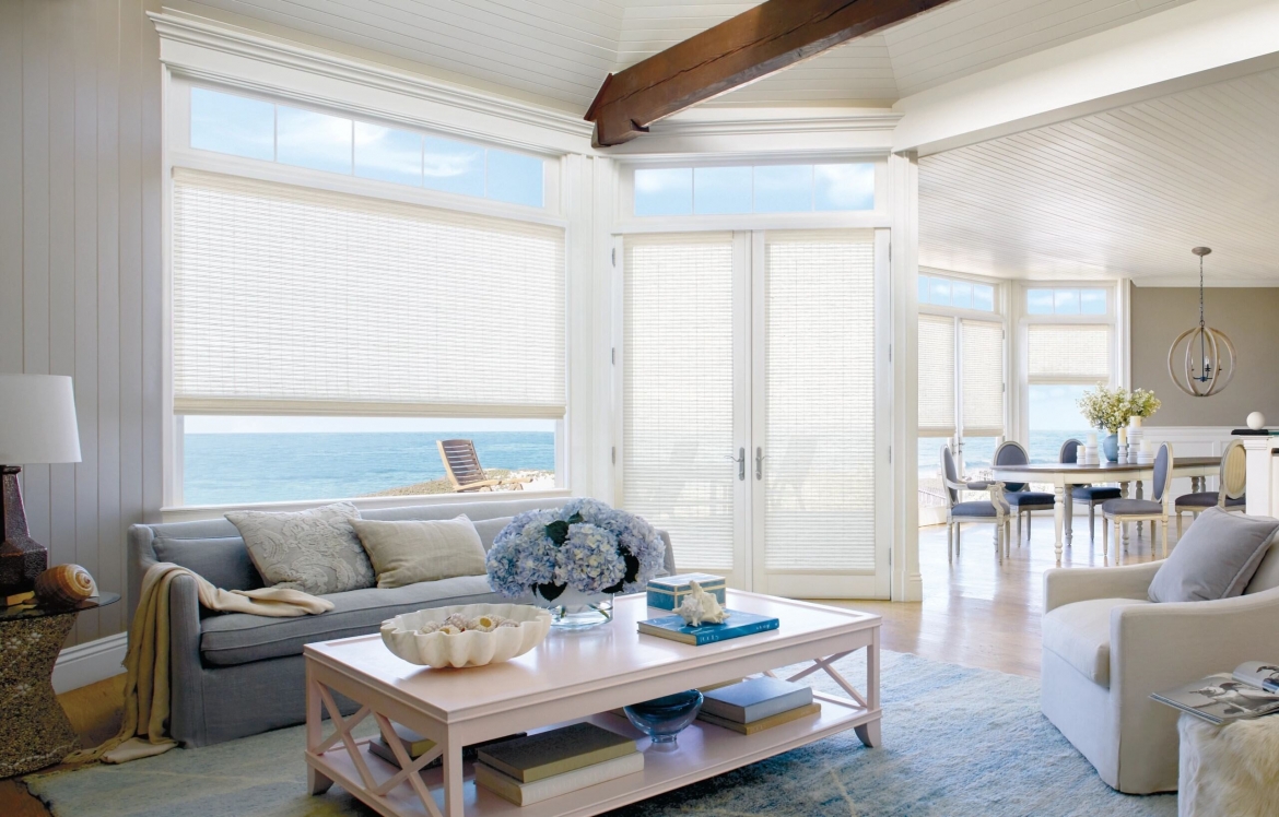 a living room with french doors to the beach covered by wooden shades