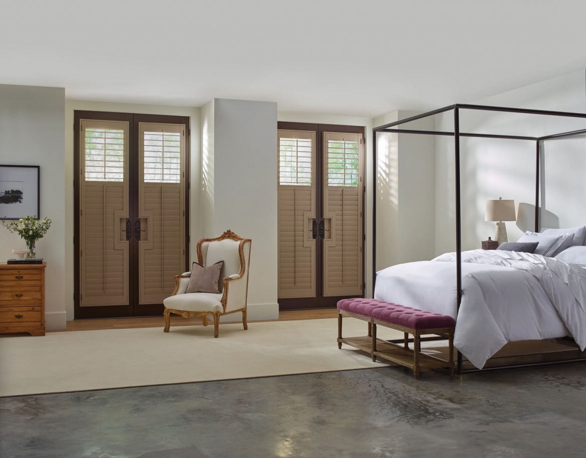 A bedroom with french doors covered by shutters